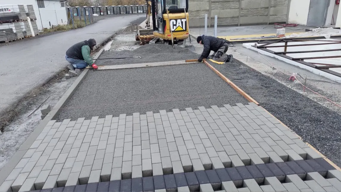 Pracovníci pokládají zámkovou dlažbu na připravený podklad